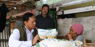 Rizal mengenakan rompi saat membagikan bantuan beras.